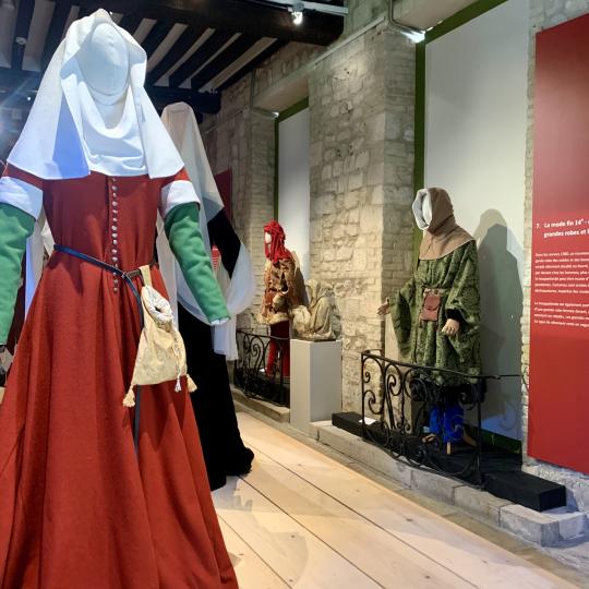 Photographie de l'exposition présentant en costume féminin, une cotte rouge du 14eme siècle.