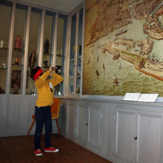 Un enfant observe à la longue vue les détails d'un plan de la ville et du port du Havre.