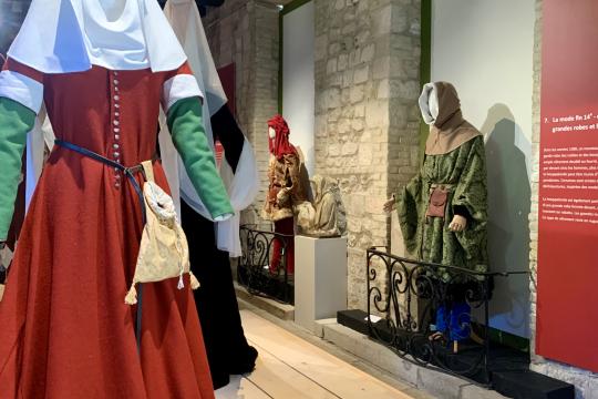 Photographie de l'exposition présentant en costume féminin, une cotte rouge du 14eme siècle.