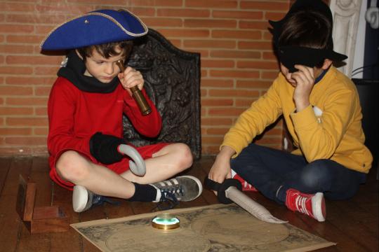 Deux enfants avec des accessoires de pirates jouent à un jeu autour d'une carte marine.